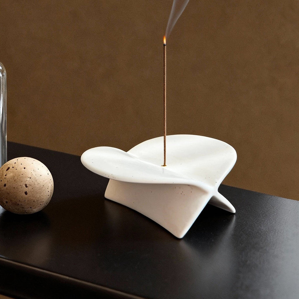 White airplane ceramic incense holder beside a warm drink